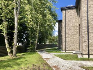 a brick building with a tree and a fence at Baltašiške in Druskininkai