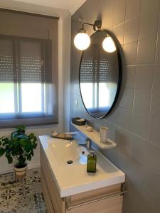 W łazience znajduje się umywalka i lustro. w obiekcie Acogedor apartamento en pleno corazón de Triana w Sewilli