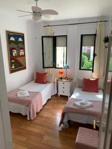 Habitación con 2 camas, mesa y ventanas. en Acogedor apartamento en pleno corazón de Triana, en Sevilla