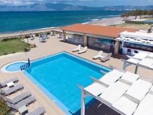 una piscina con sillas y el océano en el fondo en Captain's Beach Apartments en Kíssamos