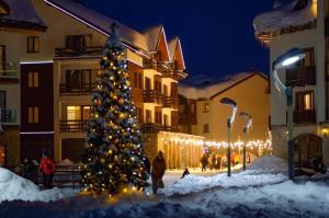 a christmas tree in front of a building with lights at Luxury hotel room with amazing views in Gudauri