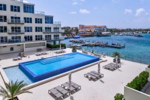 a swimming pool with a view of a body of water at Stylish luxury condo, central location, ocean view, pool, gym in Oranjestad