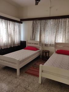 2 Betten in einem Zimmer mit Fenstern in der Unterkunft Raahgir in Nashik