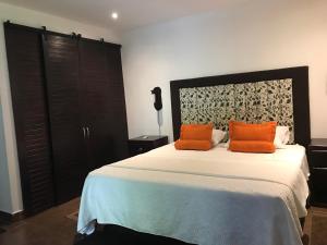 a bedroom with a bed with two orange pillows on it at Cotton House in Labrador