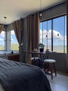 um quarto com uma cama, uma mesa e janelas em Estância Shangri-La em Santa Teresa