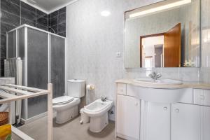 a bathroom with a sink and a toilet and a mirror at Beach House Vista Mar - Praia do Pedrógão in Coimbrão +24 photos