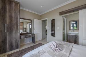 a bedroom with a bed and a bathroom with a sink at Caribbean Estates Villa Caylee - Ultra-Luxurious - Rimas Interiors Designs - Private Beachfront Escape - Premium serviced for 8 Guests in Port Edward
