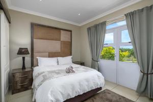 1 dormitorio con cama y ventana en Caribbean Estates Villa Caylee - Ultra-Luxurious - Rimas Interiors Designs - Private Beachfront Escape - Premium serviced for 8 Guests, en Port Edward