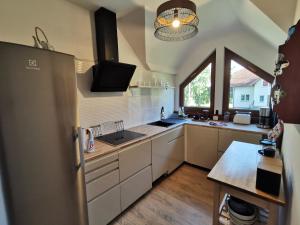 a kitchen with white cabinets and a large window at Bursztynowa 1 in Sztutowo