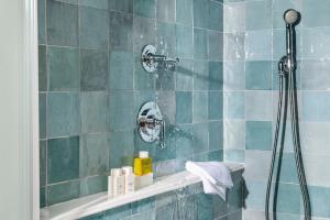 y baño con ducha de azulejos azules. en Canoe Place Inn & Cottages en Hampton Bays