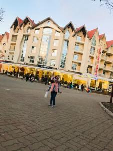 a woman standing in front of a large building at APPARTEMENT AMIRA iFRANE in Ifrane
