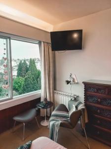 a bedroom with a window and a chair and a dresser at Giraluna Center depto con vista al lago en Bariloche in San Carlos de Bariloche
