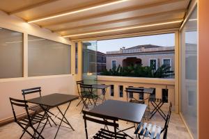 a balcony with tables and chairs and a large window at Epoch House & The Orange Shop - Adults Only in Nafplio
