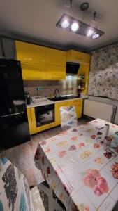 una cocina con 2 mesas y una cocina con armarios amarillos en Safta Apartaments en Cîmpulung