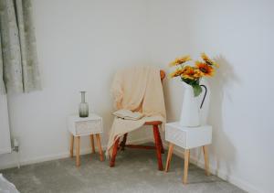 a chair and a table with a vase of flowers on it at DonVera - Two Bedroom Bungalow with Sea Views in Overcombe