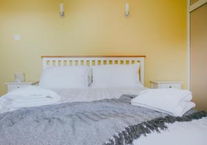 a bed with white sheets and pillows on it at DonVera - Two Bedroom Bungalow with Sea Views in Overcombe