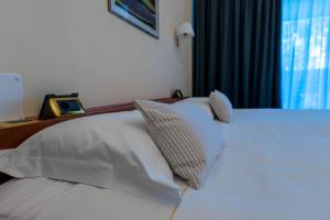 a bedroom with a bed with white sheets and pillows at Golf Hotel La Pinetina in Appiano Gentile