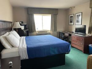 a hotel room with a bed and a desk and a television at Heritage Inn Hotel in Watertown