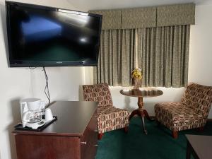a hotel room with a tv and a table and chairs at Heritage Inn Hotel in Watertown