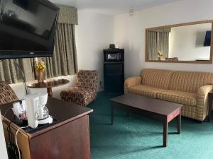 a living room with a couch and a tv in a hotel room at Heritage Inn Hotel in Watertown