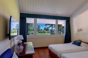 a bedroom with two beds and a large window at Golf Hotel La Pinetina in Appiano Gentile