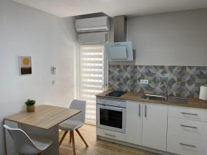 cocina con armarios blancos, mesa y fregadero en Precioso apartamento con patio/terraza Zona centro, en Jerez de la Frontera