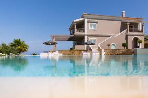 a villa with a swimming pool in front of a house at Pictures Suites in Agios Stefanos