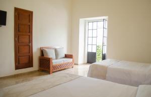 a bedroom with two beds and a chair and a window at Hotel Catedral in Cuernavaca