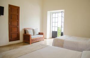 1 dormitorio con 2 camas, silla y ventana en Hotel Catedral en Cuernavaca