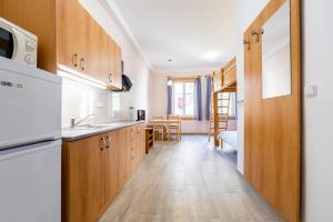 a kitchen with wooden cabinets and a dining room at Apartmány Pod Kolonádou in Janske Lazne