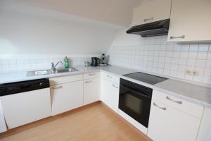 a white kitchen with a sink and a dishwasher at Stylische Ferienwohnung mit Ausblick in Haslach