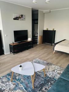 a living room with a couch and a table and a tv at 1-bedroom loft in Siena Tirgus in Rīga
