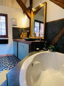 La grande salle de bains est pourvue d'une baignoire et d'un miroir. dans l'établissement La Maison Rouge Au coeur de la ville., à Riquewihr