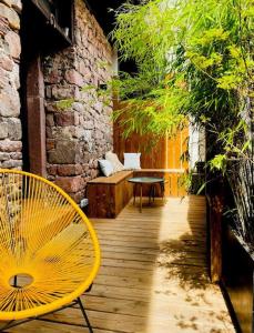 una silla amarilla y una mesa en una terraza de madera en La Maison Rouge Au coeur de la ville. en Riquewihr