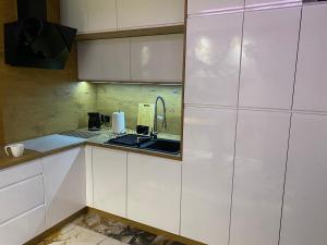 a kitchen with white cabinets and a sink at Apartament ARKANA PREMIUM in Świętochłowice