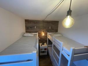 two bunk beds in a small room with a light fixture at Le cheval noir 37 (6-7 couchages ) in Valmorel