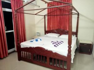 a bedroom with a four poster bed with red curtains at Asian Paradise comfort in Varca