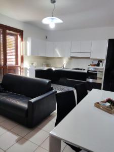 a living room with a black couch and a kitchen at Vico Stazione Apartment in Uta