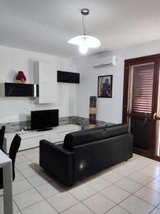 a living room with a black couch and a table at Vico Stazione Apartment in Uta