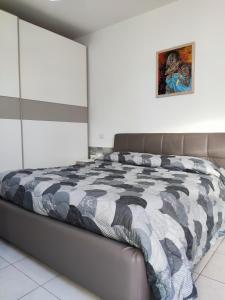 a bedroom with a bed with a black and white comforter at Vico Stazione Apartment in Uta