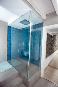 y baño con ducha de cristal y azulejos azules. en larius apartment, en Como