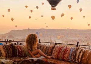 a woman sitting on a couch watching hot air balloons at Osmanli Cappadocia Hotel in Göreme