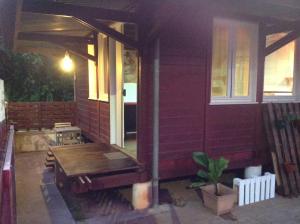 卡宴Ti case la plage的红色房子的门廊,配有木凳