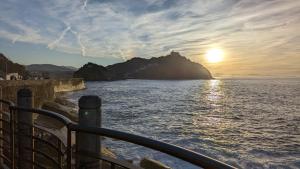 a view of the ocean with the sun setting on a mountain at Elkano Room in San Sebastián