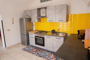una cucina con piastrelle gialle ed elettrodomestici in acciaio inossidabile di 90's House a Napoli