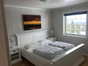 a white bedroom with two beds and a window at Stor familiehytte på Småsætra, Sjusjøen in Sjusjøen