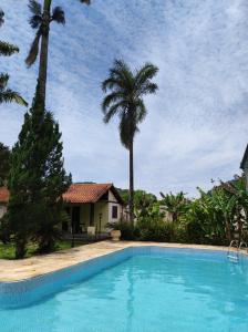 a swimming pool in front of a house with palm trees at Casa com piscina em Aldeia Velha in Quartéis