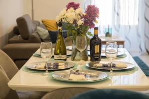 a table with two plates and wine glasses and flowers at 2 bedroom luxury design apartment in Żabbar