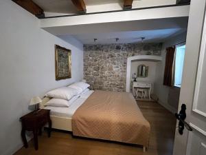 um quarto com uma cama e uma parede de pedra em Beautifully Restored 400-year Old House with Stunning Sea Views from the Terrace em Dubrovnik
