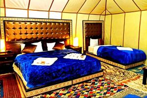 um quarto com 2 camas numa tenda em Ahlam Luxury Camp em Merzouga